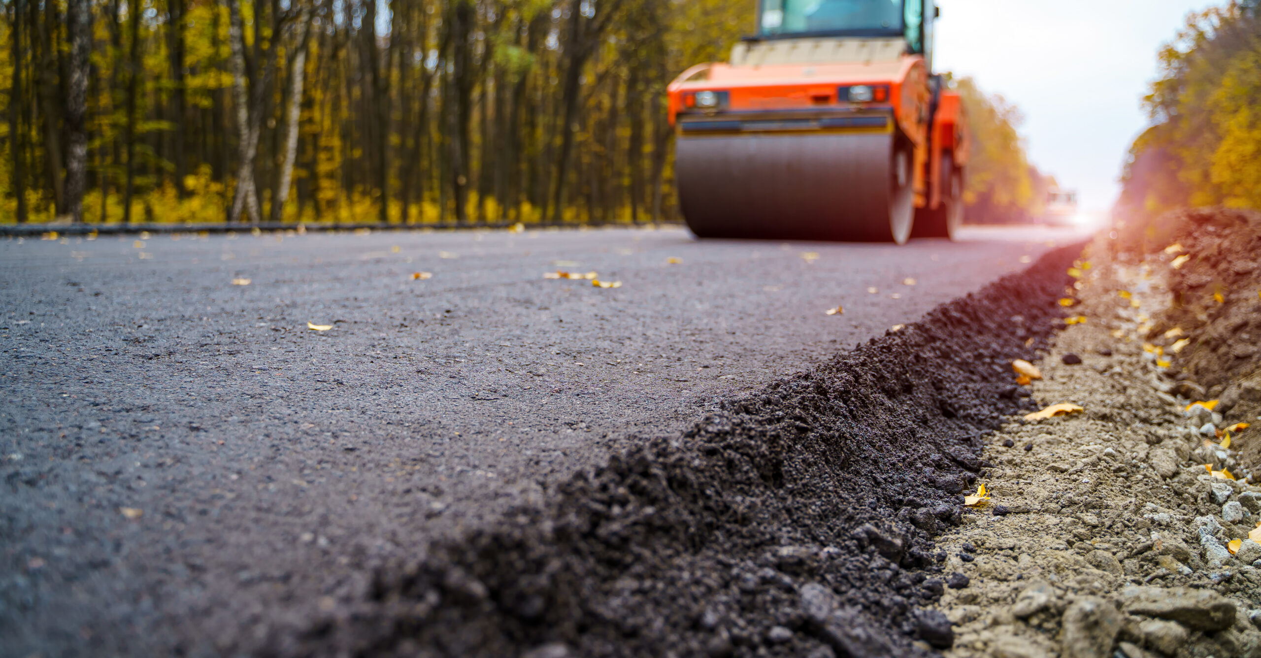 Road roller flattening new asphalt. Heavy vibration roller at work paving asphalt, road repairing. Selective focus