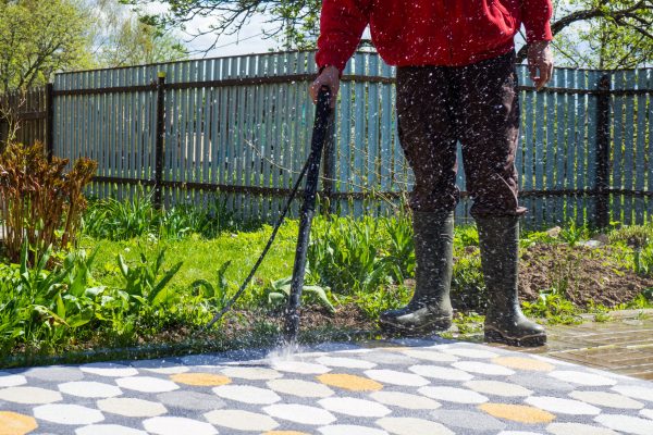 man washing carpet with pressure washer outdoors